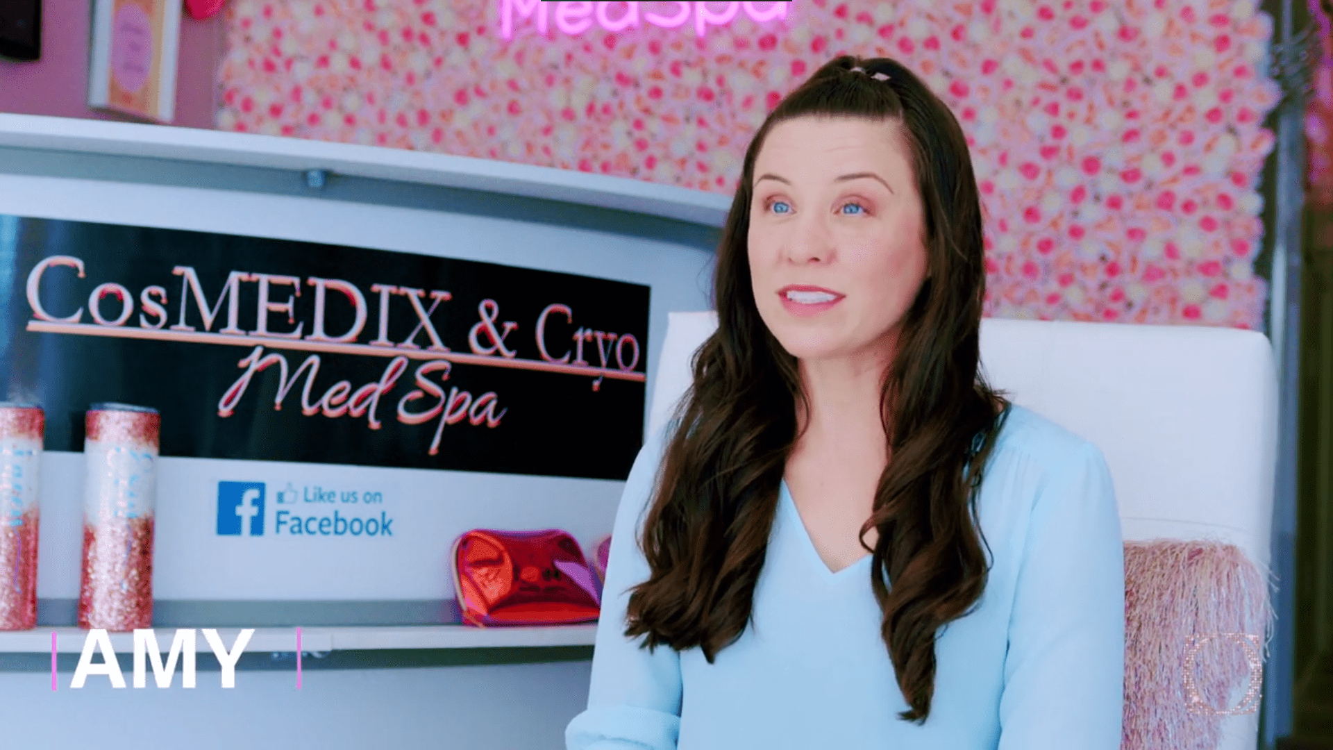 A woman sitting in front of a sign.